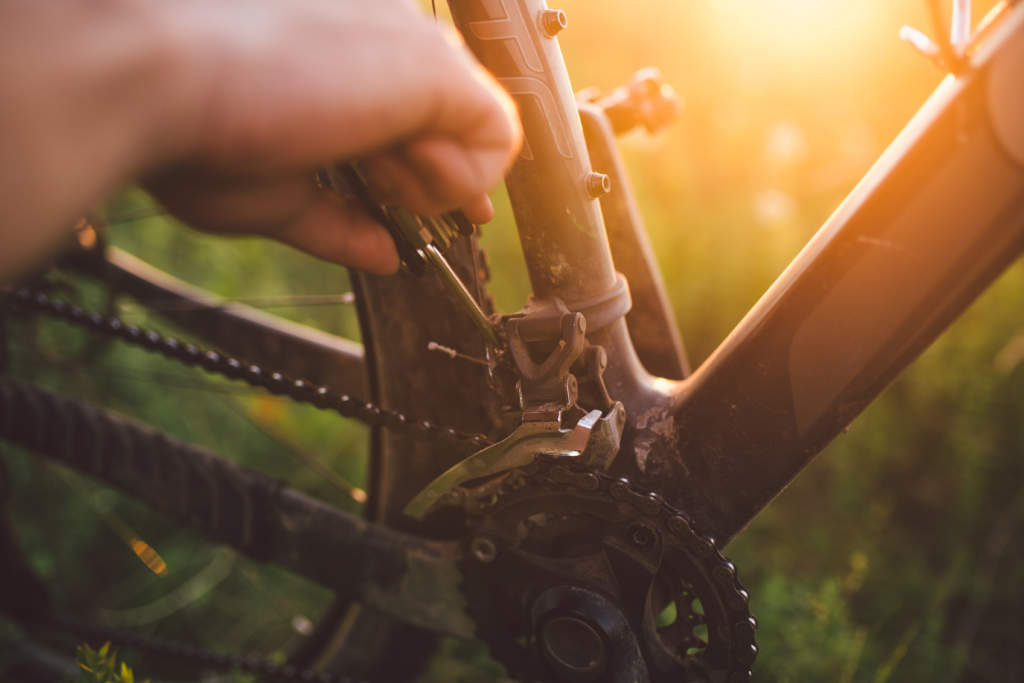 hand with a bicycle tool was engaged in fixing a bicycle outdoors at sunset close-up